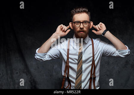 Junge stilvolle hipster Unternehmer oder Manager ist Stretching seine Ohren, imitieren Affe in eine lustige Weise oder das Vortäuschen nicht hört jemand Rede oder andere Geräusche Stockfoto