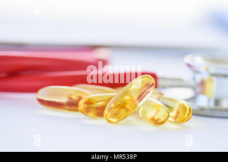 Fischöl Pillen mit Stethoskop auf weißem Hintergrund. Gesundheits- und Krankenpflege Konzept. Stockfoto