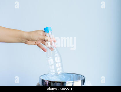 Frauen Hand werfen leere Plastikflasche in einen Papierkorb. Stockfoto