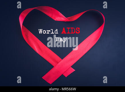 Red Ribbon, die Form eines Herzens mit Welt-AIDS Tag Text auf schwarzem Hintergrund. Stockfoto
