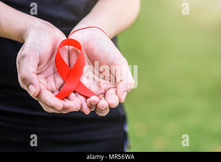 Weibliche Hände halten roten AIDS Awareness Ribbon. Aids-Aufklärungskampagne. Stockfoto