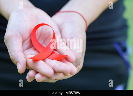 Frau Hände halten roten AIDS Awareness Ribbon. Aids-Aufklärungskampagne Stockfoto