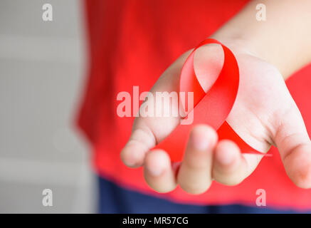 Kid Hände halten roten AIDS Awareness Ribbon. Aids-Aufklärungskampagne. Stockfoto