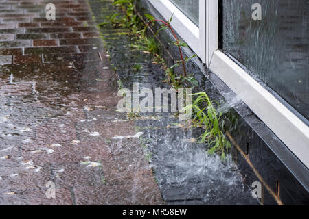 Nasses Wetter. Regen Wasser, das in einem Glas Fenster- und Spritzwasser auf dem Bürgersteig, Nottinghamshire, England, Großbritannien Stockfoto