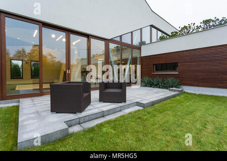 Moderne Villa mit Terrasse, Rattan Möbel und Fenster Wand Stockfoto