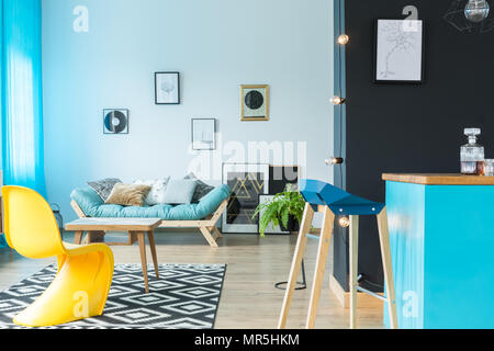 Moderne designer Barhocker an der blauen Küche Insel in farbenfrohen Wohnzimmer mit gelben Stuhl Stockfoto
