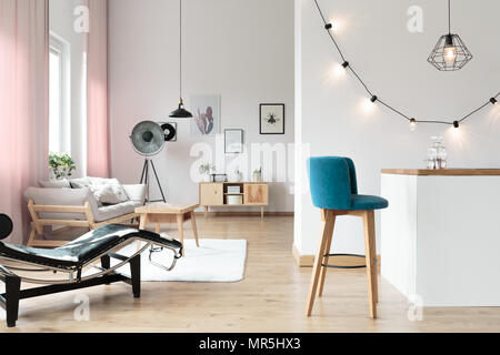 Blau Barhocker an den weißen Minibar im Wohnzimmer mit Glühbirnen auf weiße Wand und Chaiselongue Stockfoto