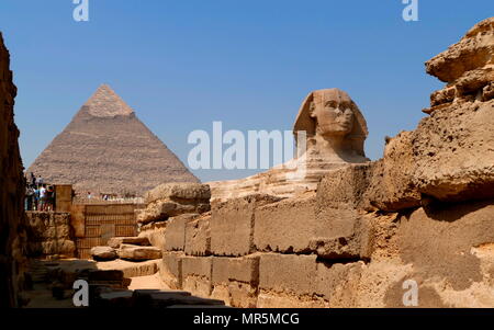 Die Große Sphinx von Gizeh gegen die Pyramide des Cheops. Kalkstein Statue eines liegenden Sphinx, ein Fabelwesen mit dem Körper eines Löwen und den Kopf eines Menschen. Direkt gegenüber von Westen nach Osten, es steht auf dem Plateau von Gizeh am Westufer des Nils in Gizeh, Ägypten. Das Antlitz der Sphinx wird allgemein angenommen, die den Pharao Khafre zu vertreten. Ausschneiden aus dem Gestein, die ursprüngliche Form des Sphinx wurde wiederhergestellt. Er misst 238 Fuß (73 m) lang (ca. 2558-2532 v. Chr.). Stockfoto