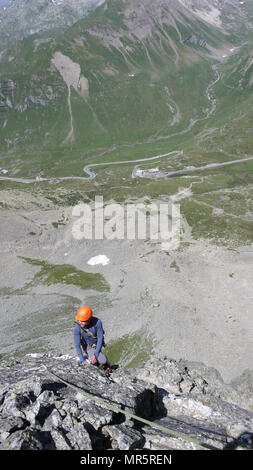 Kletterer in hellen Farben gekleidet auf einem steilen Granit Klettersteig in den Alpen Stockfoto
