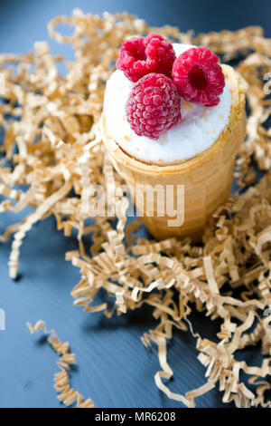 Eis mit Himbeeren im Waffle Kegel auf Holz Stockfoto