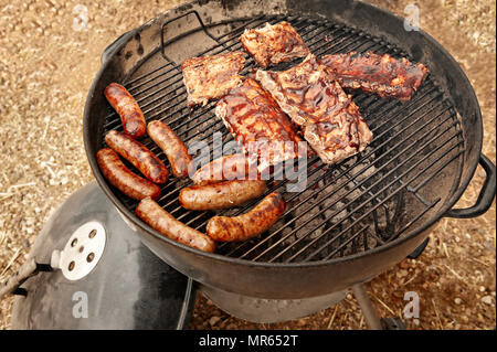 Grillen Würstchen und Racks von Rippen im Sommer auf einem Grill Holzkohle gefeuert. Stockfoto