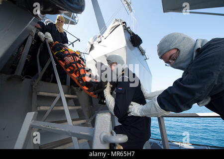 170518-N-ZE250-528 Atlantik (18. Mai 2017) Hospital Corpsman 2. Klasse Alex Penegar, links, Royal niederländischen Marine Ensign Maarten Burger eine Leiter hinunter führt, wie er eine Bahre an Bord der Arleigh-Burke-Klasse geführte Flugkörper Zerstörer USS Carney (DDG-64) beim Flag Officer Sea Training im Atlantischen Ozean trägt. Carney, vorwärts-eingesetzt in Rota, Spanien, führt seine dritte Patrouille in den USA 6. Flotte Bereich der Maßnahmen zur Erhöhung der Sicherheit der Vereinigten Staaten in Europa interessiert. (Foto: U.S. Navy Mass Communication Specialist 3. Klasse Weston Jones/freigegeben) Stockfoto