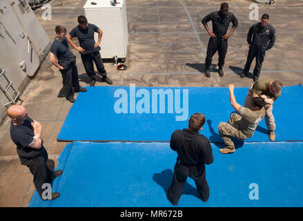 Gunnery Sgt. Arvin Manning, Personal noncommissioned Officer zuständig für die Strafverfolgung Loslösung, 24 Marine Expeditionary Unit (MEU), zeigt einen Arm Manipulation takedown Technik auf Lance Cpl. Leonardo Castillo, ein militärischer Polizist, während eine nicht tödliche Klasse als Teil des Master-at-arms Ausbildung an Bord amphibious Transport dock Schiff USS Mesa Verde LPD (19) 18. Mai 2017. Die 24. MEU ist mit dem Bataan Amphibious Ready Gruppe unterwegs in der Unterstützung der Maritime Security Operations und Theater Sicherheit Zusammenarbeit in den USA 6 Flotte Bereich der Operationen. (U.S. Marine Corps Foto von G Stockfoto