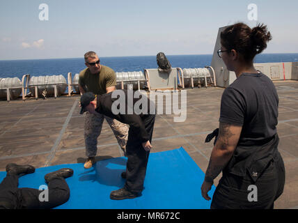 Gunnery Sgt. Arvin Manning, Personal noncommissioned Officer zuständig für die Strafverfolgung Loslösung, 24 Marine Expeditionary Unit (MEU), erklärt zum Elektriker Mate 3. Klasse Lujain Alshaikhkhaleel die Schritte zur Ausführung eines arm Manipulation Technik während es demonstrieren, während eine nicht tödliche Klasse als Teil des Master-at-arms Ausbildung an Bord amphibious Transport dock Schiff USS Mesa Verde LPD (19) 18. Mai 2017. Die 24. MEU ist mit dem Bataan Amphibious Ready Gruppe unterwegs in der Unterstützung der Maritime Security Operations und Theater Sicherheit Zusammenarbeit in den USA 6 Flotte Einsatzgebiet Stockfoto