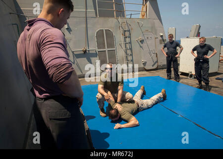 Gunnery Sgt. Arvin Manning, Personal noncommissioned Officer zuständig für die Strafverfolgung Loslösung, 24 Marine Expeditionary Unit (MEU), erklärt die Schritte zur Ausführung eines arm Manipulation Technik demonstriert es auf Sgt. Steven Eakes, ein militärischer Polizist, während eine nicht tödliche Klasse als Teil des Master-at-arms Ausbildung an Bord amphibious Transport dock Schiff USS Mesa Verde LPD (19) 18. Mai 2017. Die 24. MEU ist mit dem Bataan Amphibious Ready Gruppe unterwegs in der Unterstützung der Maritime Security Operations und Theater Sicherheit Zusammenarbeit in den USA 6 Flotte Bereich der Operationen. (U.S. Marin Stockfoto