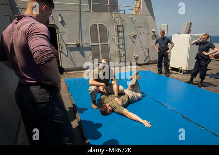 Gunnery Sgt. Arvin Manning, Personal noncommissioned Officer zuständig für die Strafverfolgung Loslösung, 24 Marine Expeditionary Unit (MEU), erklärt die Schritte zur Ausführung eines arm Manipulation Technik demonstriert es auf Sgt. Steven Eakes, ein militärischer Polizist, während eine nicht tödliche Klasse als Teil des Master-at-arms Ausbildung an Bord amphibious Transport dock Schiff USS Mesa Verde LPD (19) 18. Mai 2017. Die 24. MEU ist mit dem Bataan Amphibious Ready Gruppe unterwegs in der Unterstützung der Maritime Security Operations und Theater Sicherheit Zusammenarbeit in den USA 6 Flotte Bereich der Operationen. (U.S. Marin Stockfoto