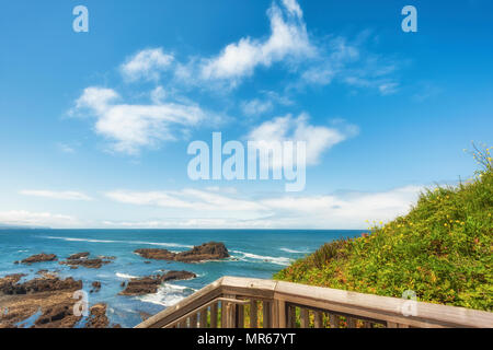 Blick auf den Pazifischen Ozean mit blauem Himmel und weißen Wolken über dem Meer Wasser bestreut mit geologischen Eigenschaften auf Kopfsteinpflaster Strand bei Yaquina Head Lighthous Stockfoto