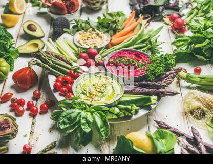 Gesunde Rohstoffe Sommer veganen Snack plate. Kichererbsen, rote Beete, Spinat Hummus Dips mit bunten frisches Gemüse und Grüns auf weißem Hintergrund. Cle Stockfoto