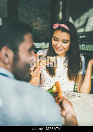 Junge glücklich kaukasischen Paar am Tisch essen Pizza in der Italienischen Küche Cafe an sonnigen Sommertagen sitzen Stockfoto