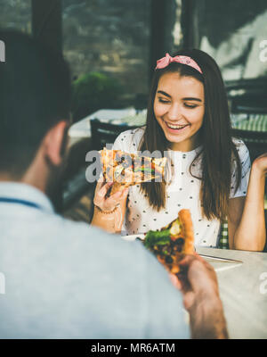 Junge glücklich kaukasischen Paar sitzen am Tisch frisch gebackene Pizza essen und trinken Rotwein in Outdoor italienische Küche Cafe auf klaren sonnigen Sommer d Stockfoto