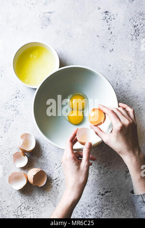 Womans Hände trennen Eier weiß von Eigelb, mit einer Schüssel Stockfoto