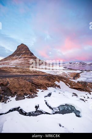 Kirkjufell Berg, Kirkjufellfoss Wasserfall vor, bewölkter Himmel mit Sonnenuntergang gefroren, Grundarfjördur Fjord, Western Island Stockfoto