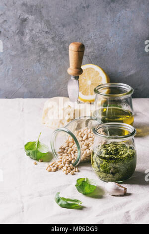 Traditionelle Basilikum Pesto in Glas Glas mit Zutaten oben Basilikum, Olivenöl, Parmesan, Knoblauch, Pinienkernen, lemon am Küchentisch mit Wh Stockfoto