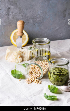 Traditionelle Basilikum Pesto in Glas Glas mit Zutaten oben frisches Basilikum, Olivenöl, Parmesan, Knoblauch, Pinienkernen, lemon am Küchentisch w Stockfoto