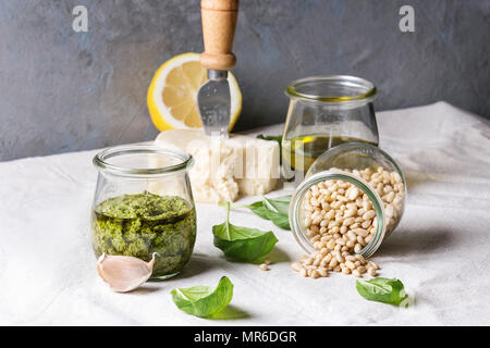 Traditionelle Basilikum Pesto in Glas Glas mit Zutaten oben frisches Basilikum, Olivenöl, Parmesan, Knoblauch, Pinienkernen, lemon am Küchentisch w Stockfoto