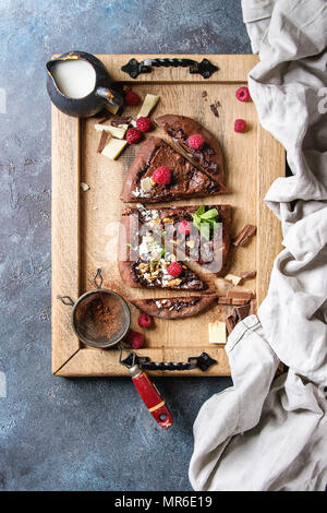 Hausgemachten süßen Dessert Schokolade Pizza mit verschiedenen Schokoladen, Himbeeren und Minze serviert auf einem Tablett mit Tuch und Zutaten oben über Blu Stockfoto