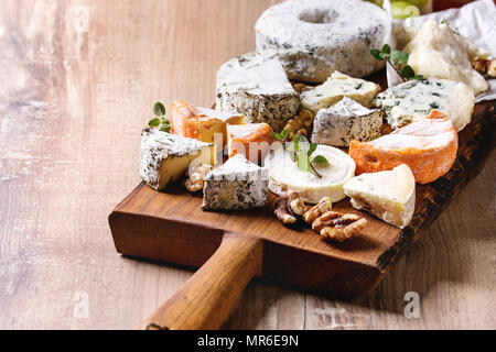 Käseplatte Sortiment an französischen Käse serviert mit Honig, Nüssen, Brot und Trauben auf rustikalen Holzmöbeln serviert Board über Holz Textur Hintergrund. Clo Stockfoto