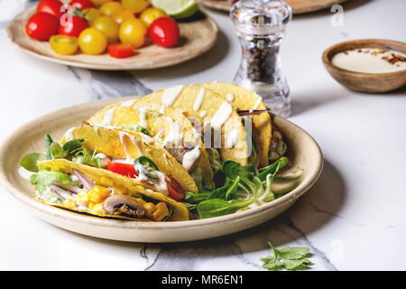 Auswahl an vegetarischen Mais Tacos mit Gemüse, Salat, Chili Pfeffer auf Keramikteller mit Tomaten und Sahne Saucen mit Zutaten serviert abov Stockfoto