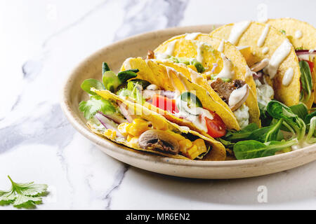 Auswahl an vegetarischen Mais Tacos mit Gemüse, Salat, Chili Pfeffer auf Keramikteller mit Tomaten und Sahne Saucen mit Zutaten serviert abov Stockfoto