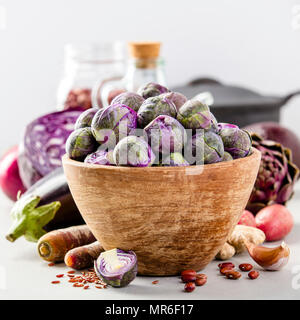 Lila Rosenkohl in eine Schüssel und gesunden Zutaten auf konkreten Hintergrund. Vegan, glutenfrei, allergikerfreundliche, sauber essen oder raw-Diät. Spac Stockfoto