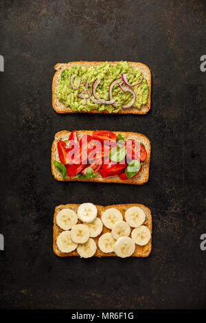 Verschiedene Arten von bunten Vollkorn Brot Sandwiches auf dunklem Hintergrund von oben (Ansicht von oben). Sauber, Essen, gesund, Ernährung, Gewichtsreduktion Essen conce Stockfoto