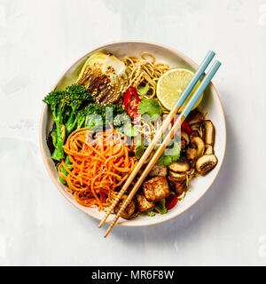 Vegetarische Nudeln mit Tofu, Brokkoli, Champignons, Karotten, Bok Choy am weißen Stein. Ansicht von oben, flach, Copyspace Stockfoto