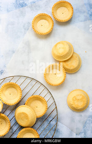 Kleines gebackenes Gebäck tartlet Fällen Kühlung in einem Draht Rack und Backpapier. Stockfoto