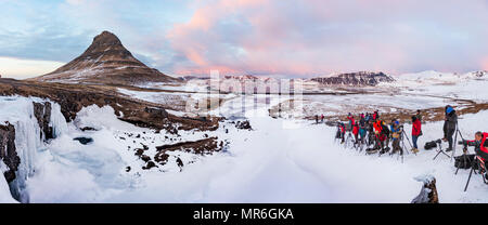 Viele Fotografen Foto Mount Kirkjufell mit gefrorenen Wasserfall Kirkjufellfoss, bewölkter Himmel bei Sonnenuntergang Stockfoto