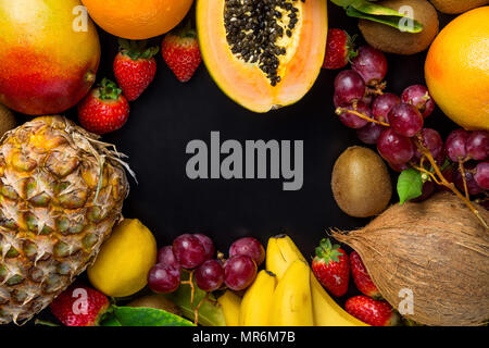 Rahmen mit Kopieren aus frischen tropischen und Sommer saisonale Früchte Ananas Papaya Mango Coconut Orangen, Kiwi, Bananen, Zitronen Pampelmusen und Grapefruits auf Schwarz Ba Stockfoto