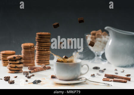 Kaffeetasse mit Spritzwasser Rohrzucker auf Tabelle mit Cookies und Gewürze Stockfoto