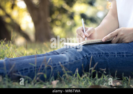 Nahaufnahme junge Frauen schreiben auf Notebook im Park, Konzept in Bildung und Wissen Stockfoto