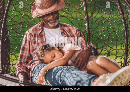 Kleine afrikanische amerikanische Enkelin schlafen auf Runden von Großvater in Schwingen Hängesessel Stockfoto