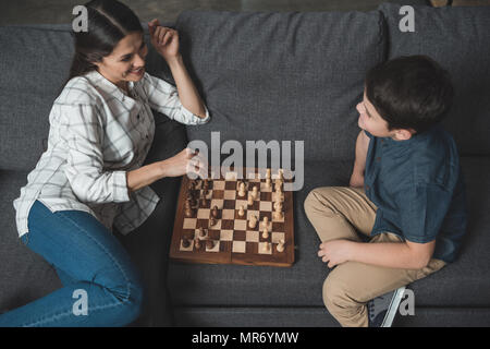 Junge Frau bewegt sich in Schach Spiel mit ihrem Sohn auf der Couch im Wohnzimmer. Stockfoto