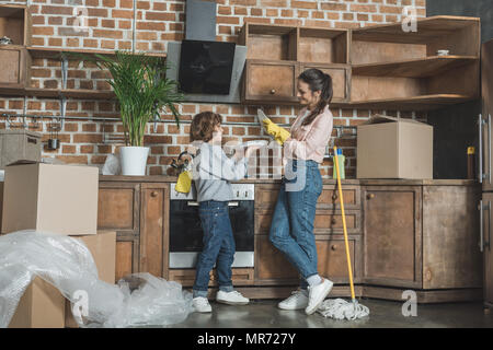 Mutter und Sohn lächelnd gegenseitig beim Waschen Platten nach Umzug in neue Wohnung Stockfoto