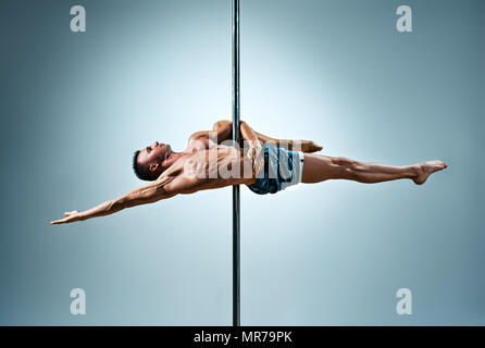 Junge starke Pole dance Mann auf Wand Hintergrund Stockfoto