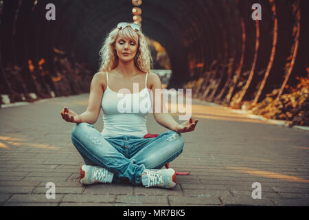 Junge Teenager Stil Frau im City Park und der Meditation zu sitzen. Film style Farben. Stockfoto