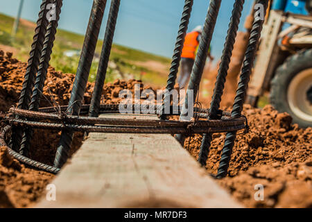 Stange aus Stahl für Masten Konstruktion mit Beton verstärkt in ein Loch im Boden auf der Baustelle. Stockfoto