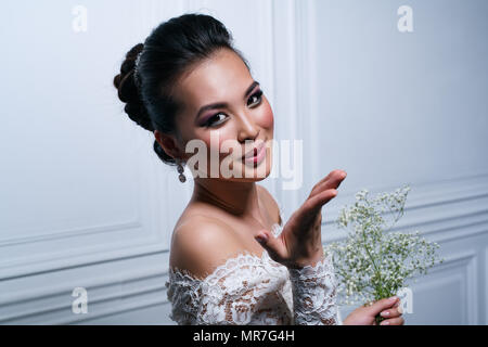 Junge asiatische Frau in weißem Kleid mit Blumen Luft kiss Porträt posieren Stockfoto