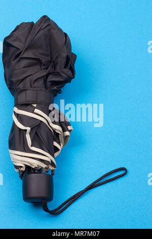Geschlossen schwarz Regenschirm auf dem blauen Hintergrund Stockfoto
