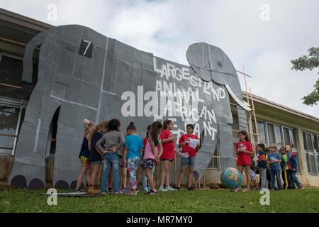 Kinder von Kadena Volksschule versammeln sich um einen Karton Ausschnitt der größten Land der Welt - zu Fuß Tier, einem afrikanischen Elefanten, 22. Mai 2017, bei Kadena Air Base, Japan. Die Veranstaltung, die von der Schule Englisch als zweite Sprache Team produziert und wurde gehalten, fächerübergreifende Themen wie Wissenschaft, Gesundheit, Geschichte und Geographie zu unterrichten. (U.S. Air Force Foto von älteren Flieger John linzmeier) Stockfoto